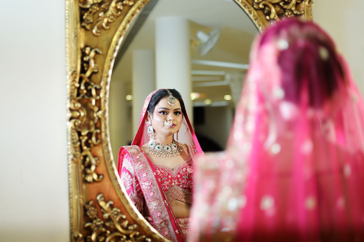 Stock stand-in: a bride in embroidered attire seeing herself in a gilded mirror